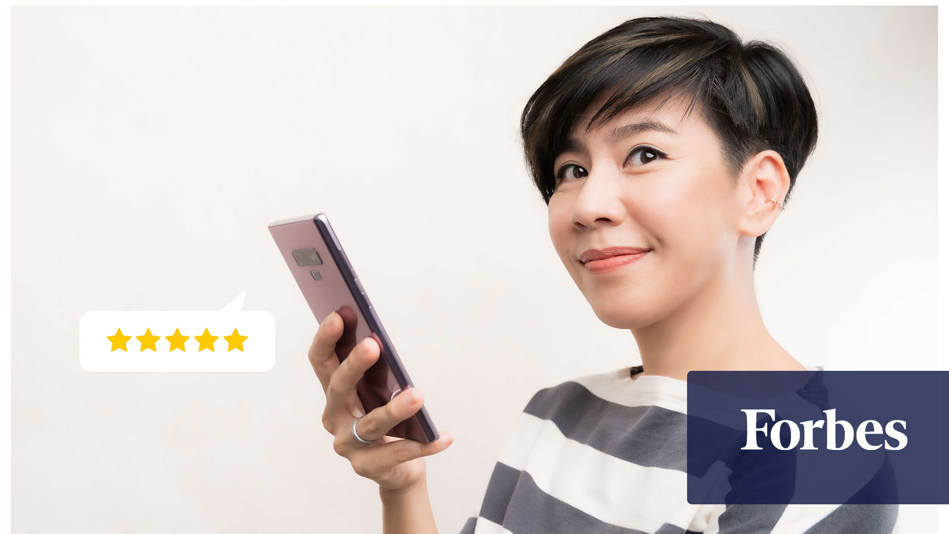 A smiling woman holds a phone with a five-star rating in a text bubble