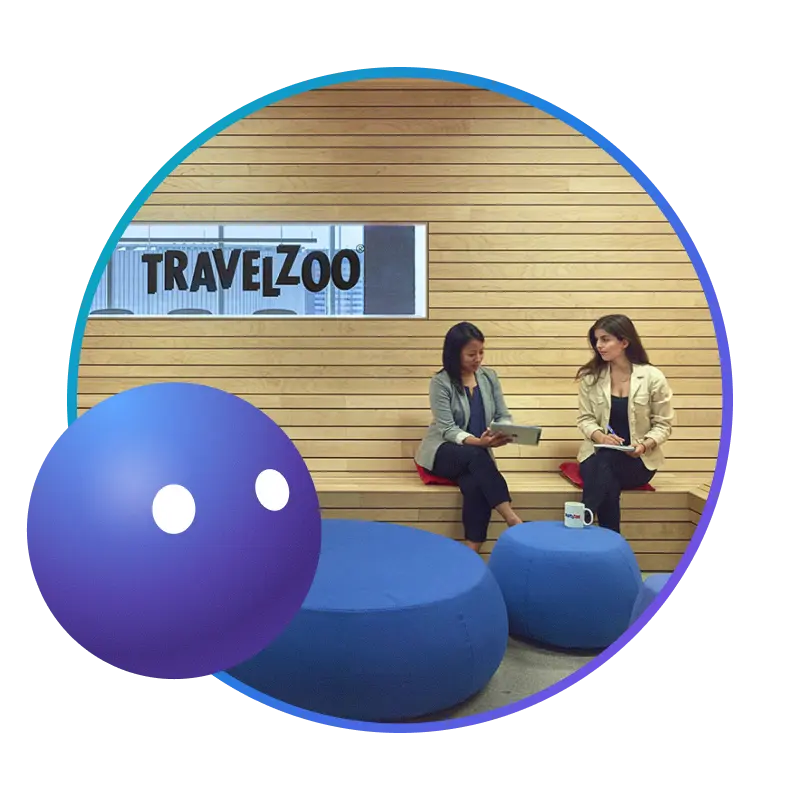 Two colleagues talking in front of a Travelzoo sign